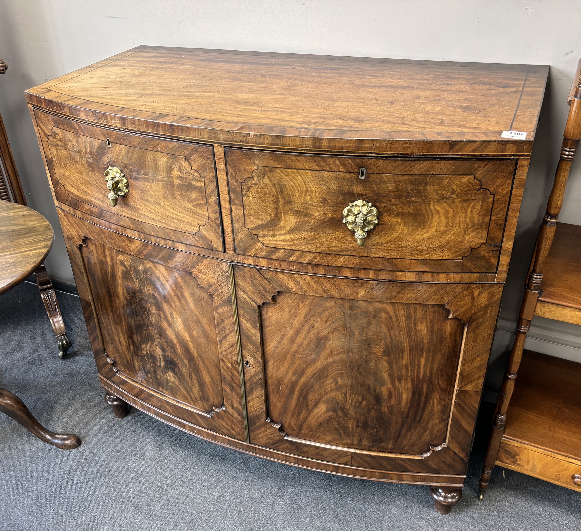 A George IV flame figured mahogany bowfront press cupboard, width 115cm, depth 61cm, height 108cm